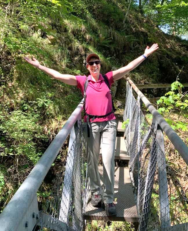 Susanne Furler mit ausgebreiteten Armen auf einer Hängebrücke – Lebensfreude und Aufbruchsstimmung.