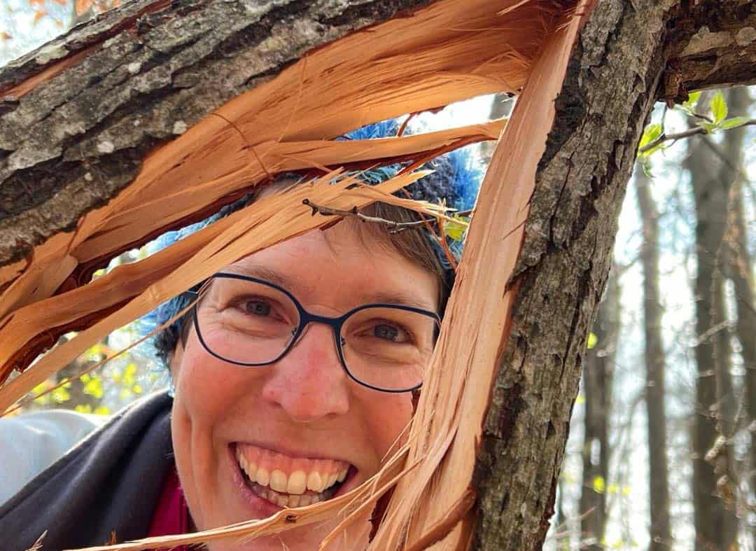 Susanne Furler schaut durch einen gespaltenen Ast.